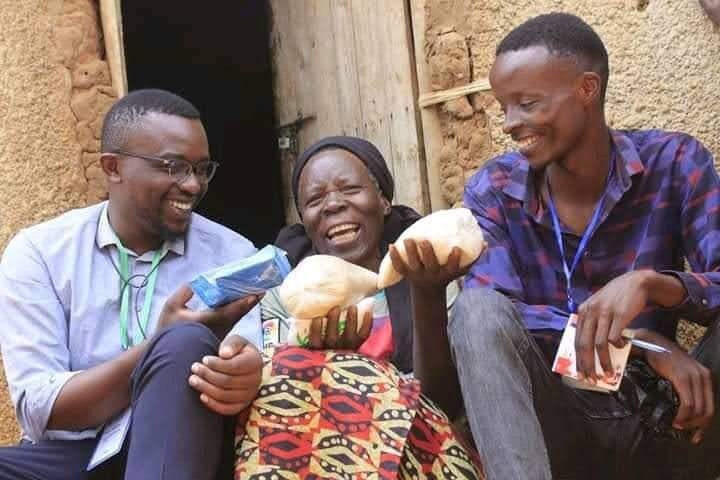 An elderly woman laughing with two YRUD members during a joyful home visit