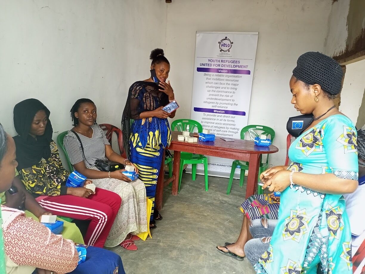 Women seated in a session on menstrual health beneath the YRUD banner